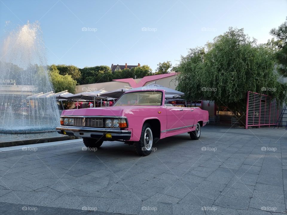 Pink soviet old-timer car next to a fountain