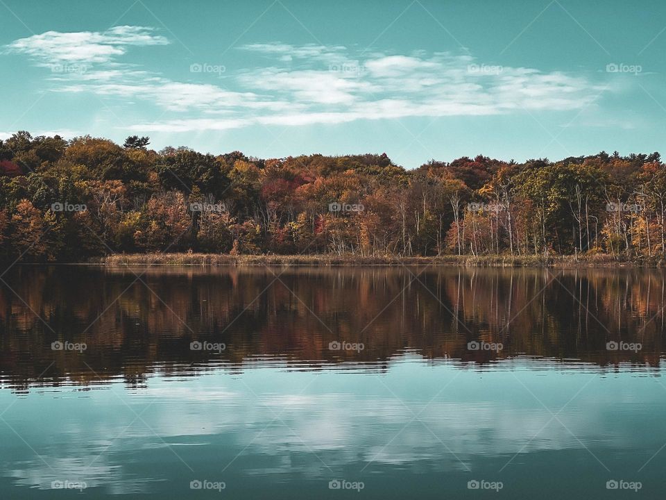 Autumn landscape, colorful leaves at Upstate New York. Clouds background on sunny day reflection in water.