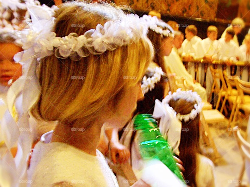 Students attended A procession of young girls in white dresses and wreaths in the monastery of Jasna Góra in Częstochowa Poland. Here, one girl quietly contemplates the ceremony before she begins.  