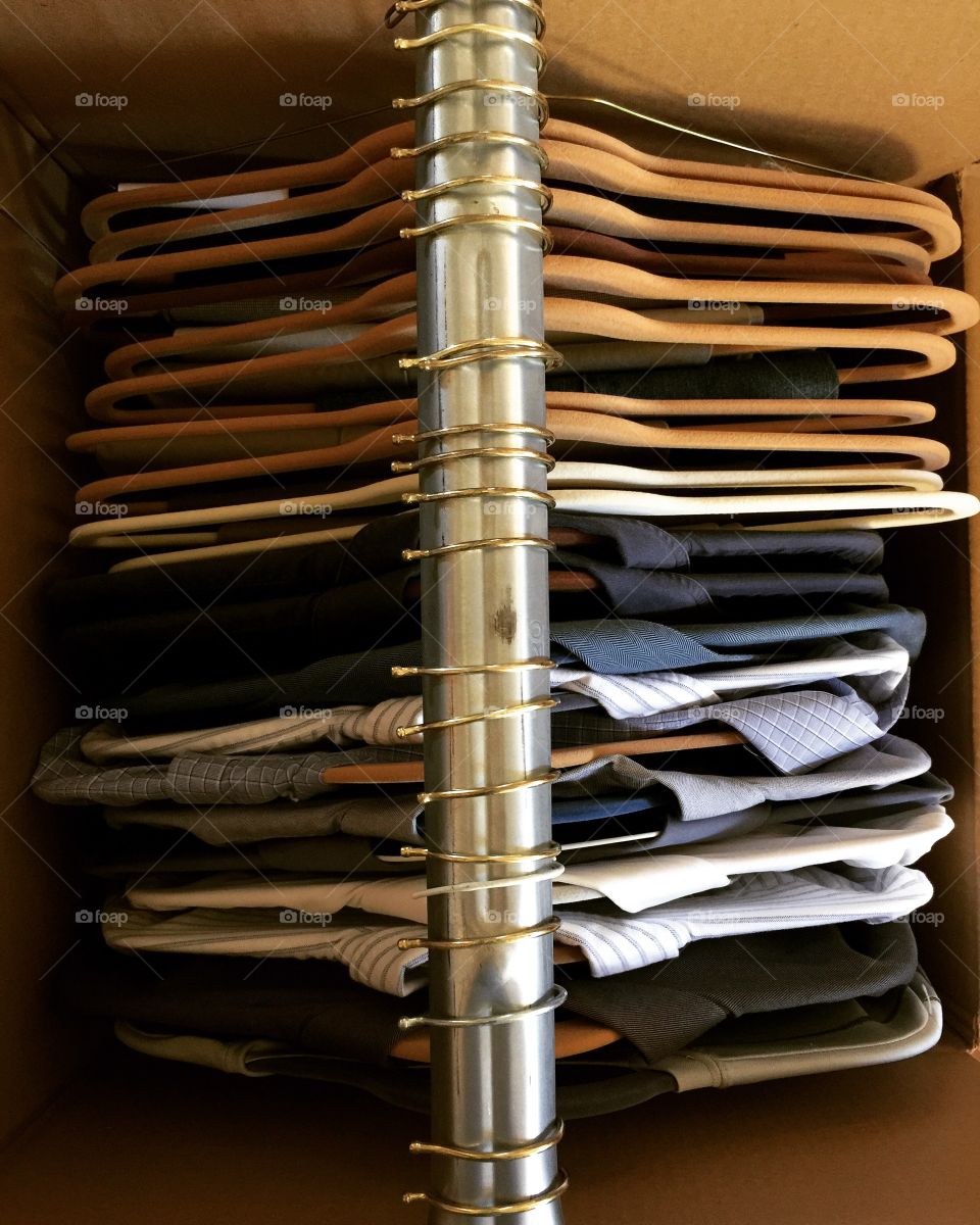 Clothing apparel on tan huggable hangers stored inside moving box