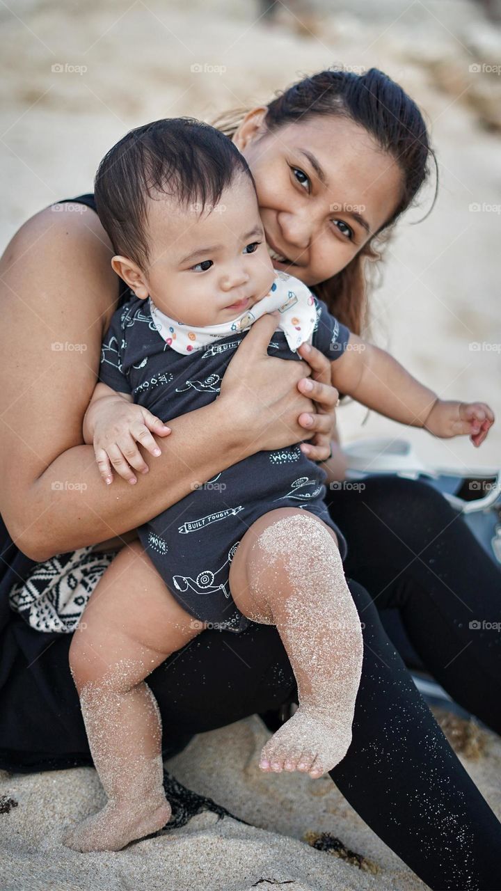 Mom and son play sand and having fun together at beach