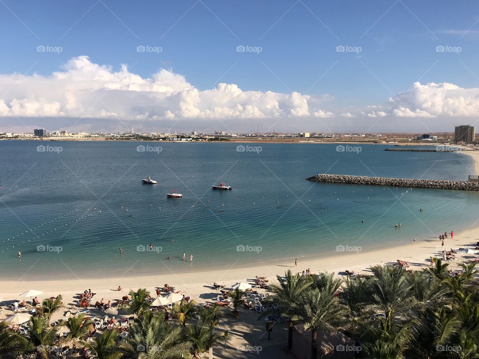 People enjoying the morning sun on a man made beach in Ras Al Khaimah (UAE) in a beach resort