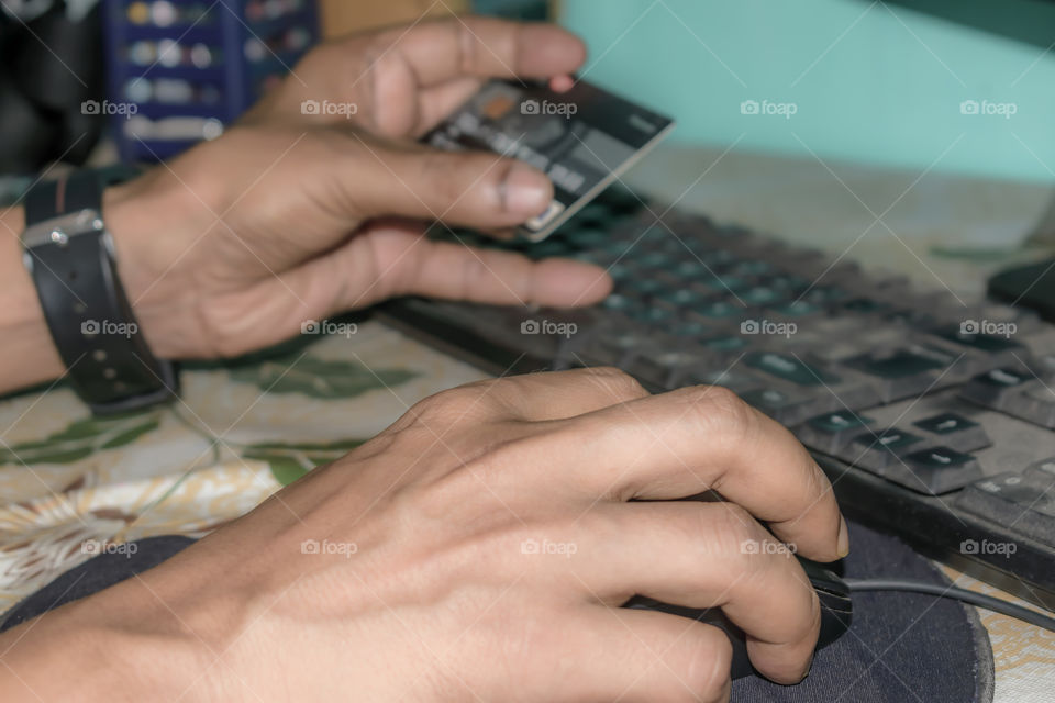 Businessman holding plastic credit card in hand and using laptop computer. Man making online shopping concept. Close up hands holding a credit card and touching a screen as an on-line shopping.