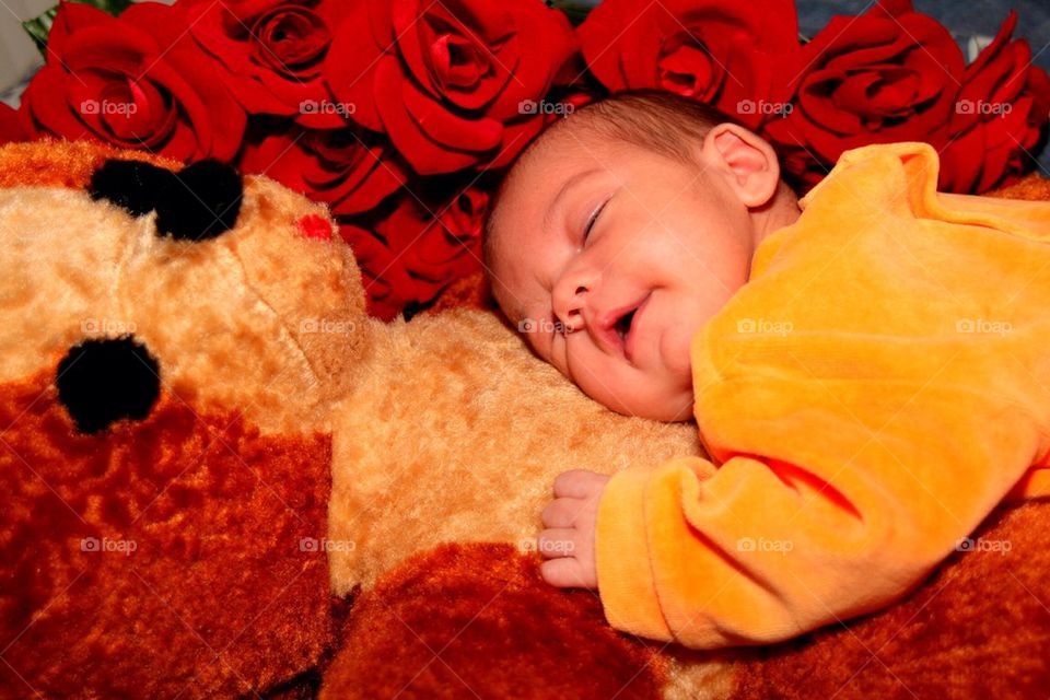 Baby curling up to teddybear