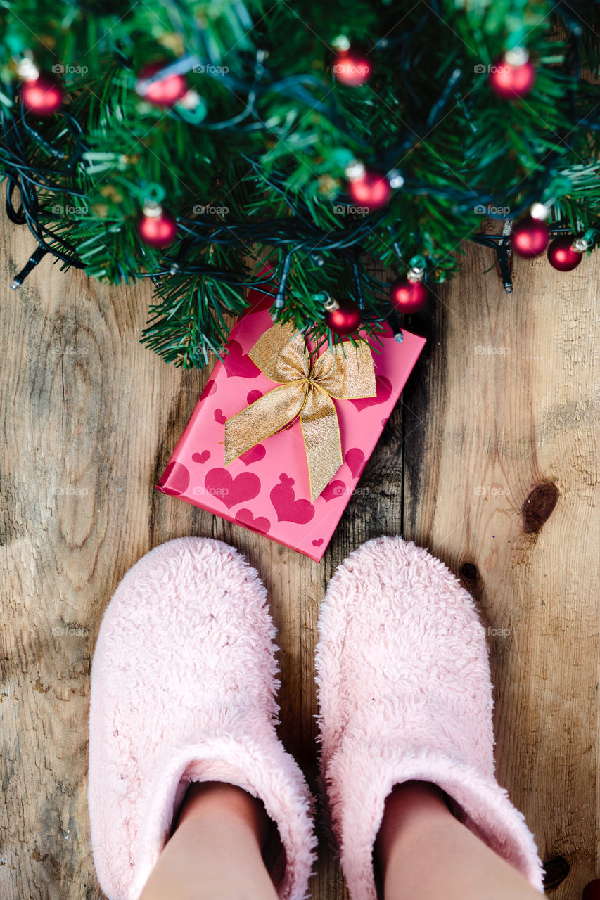 Child looking down at present under Christmas tree