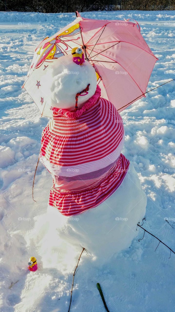 A very original snowman with a pink dress and a pink umbrella