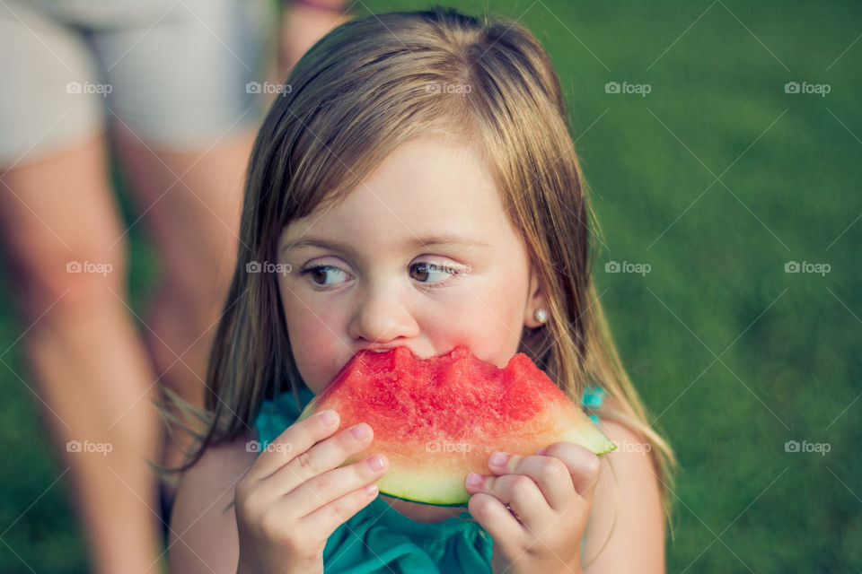 Young Girl Eating Watermelon Outside at Park 