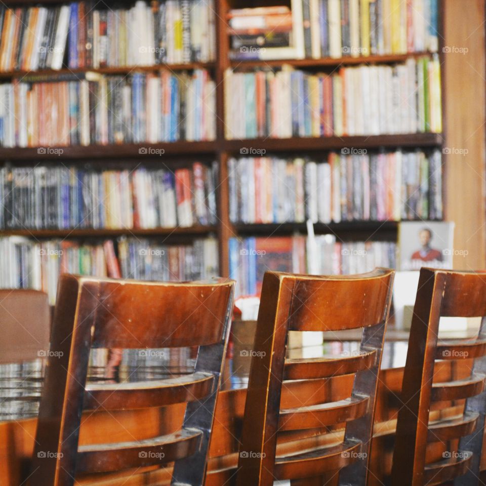 well used brown wooden chairs in front of a well stocked bookcase