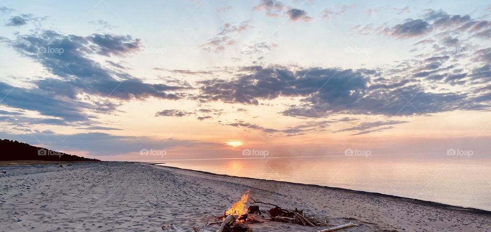 A campfire  during sunset sunset n a Sandy beach on the shores of Lake Superior in the upper peninsula of Michigan