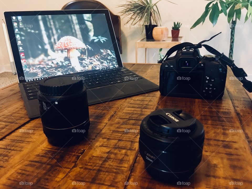 Modern digital photography camera equipment next to a sleek laptop on a wooden table 