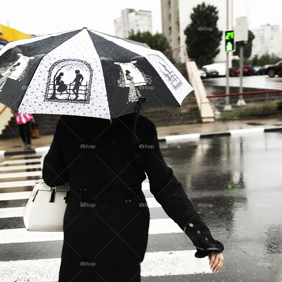 Woman wearing Black and white fashionable clothes and umbrella under the rain 