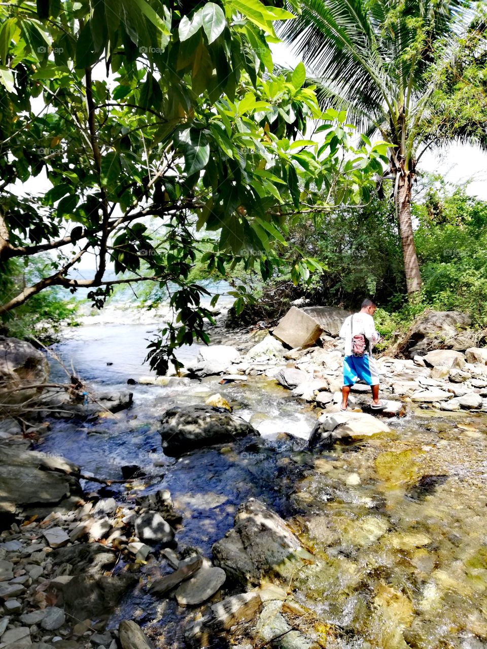 Crossing a river, flowing into the sea, with a local guide while hiking to far away places in Abra De Ilog, Mindoro, Island of Philippines