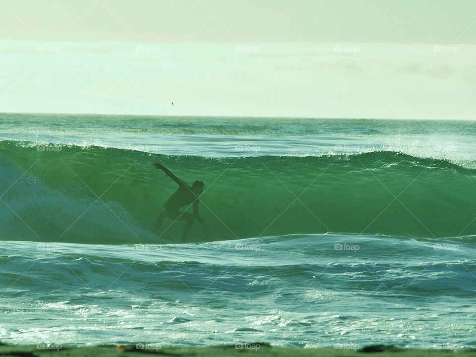Evening surfer captured appearing imbedded inside the wave.