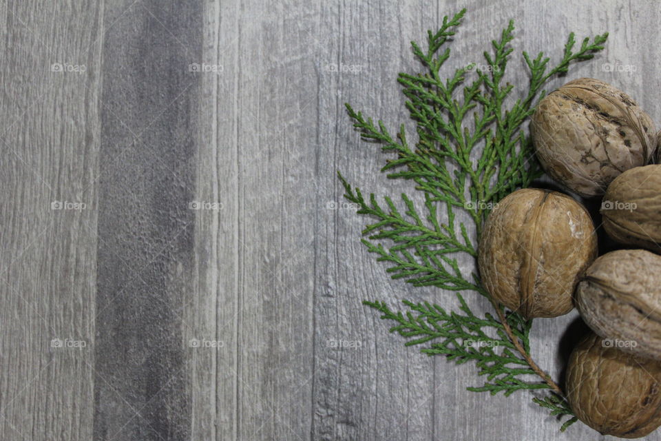 Walnuts and green branch on wooden background.