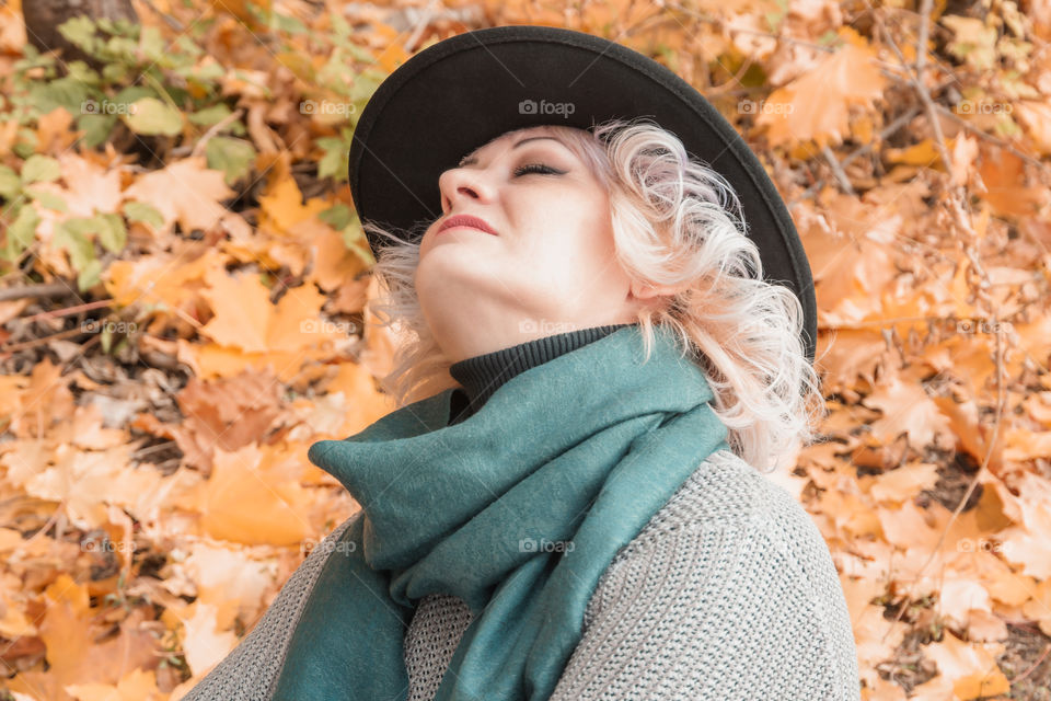 Autumn portrait of adult middle-aged relaxing woman in black hat and autumn clothes