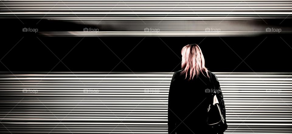 Woman standing at a station as a train whizzes past 