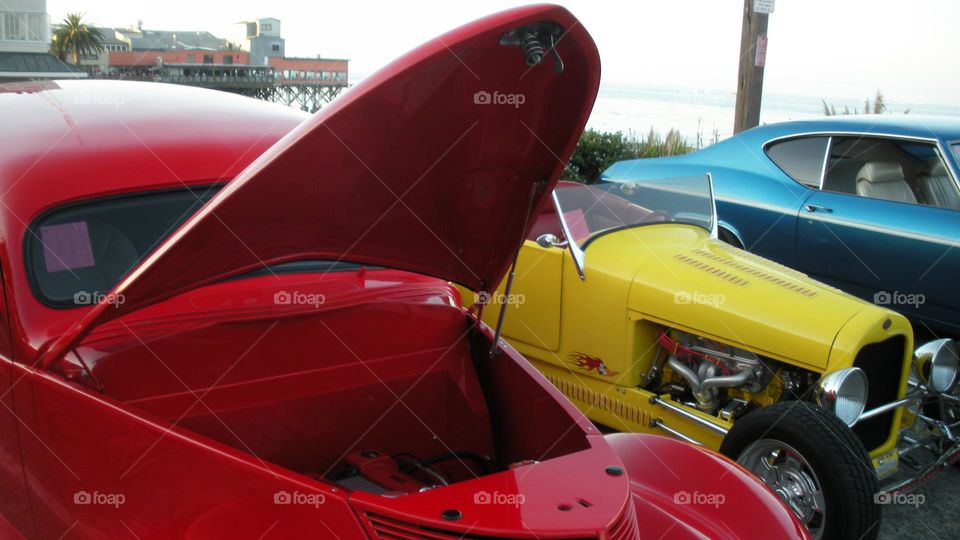 red car with open hood in line of colorful cars in outdoor California classic car show