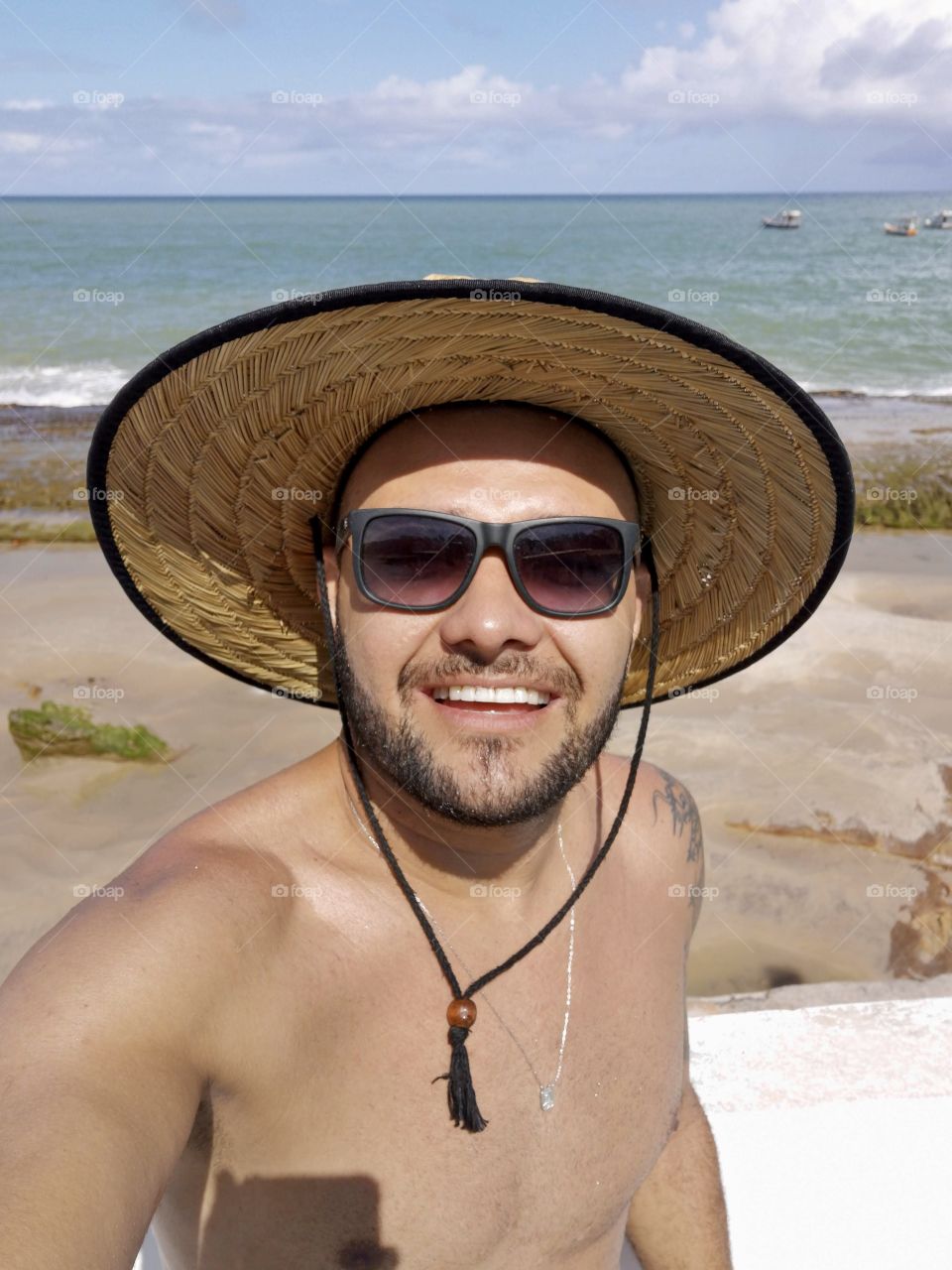 Beach hat man smiling with sea in the background