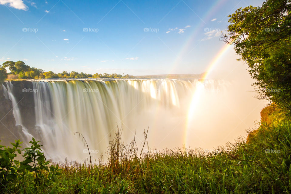 Beautiful late afternoon slow shutter image of waterfall in Africa with rainbows and grass