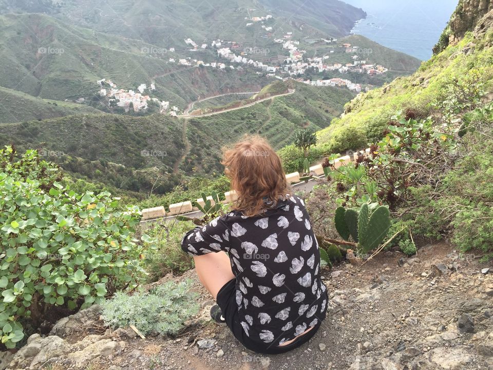 A girl sitting on a top of the mountain and thinking about the sense of life