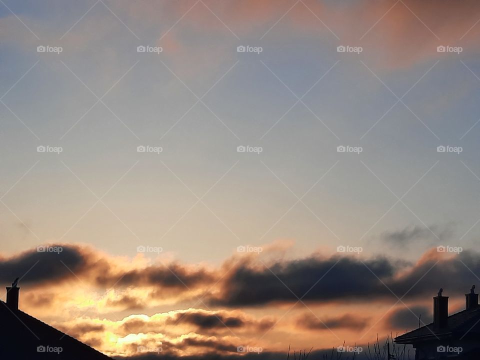 sunrise with black and pink clouds  and black silhouette of houses