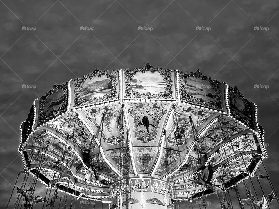 Black and white photo of a chain carousel with sky in the background