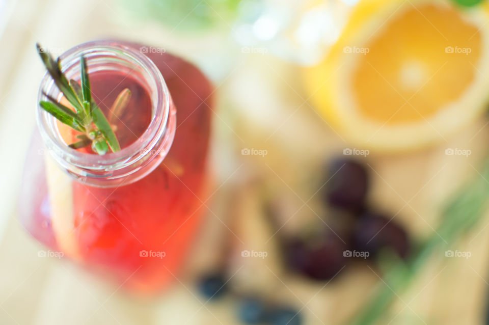 Elevated view of fresh homemade flavored water with rosemary herb on bright wood background with citrus fruit, cherry and berries selective focus with room for copy space healthy drinks photography