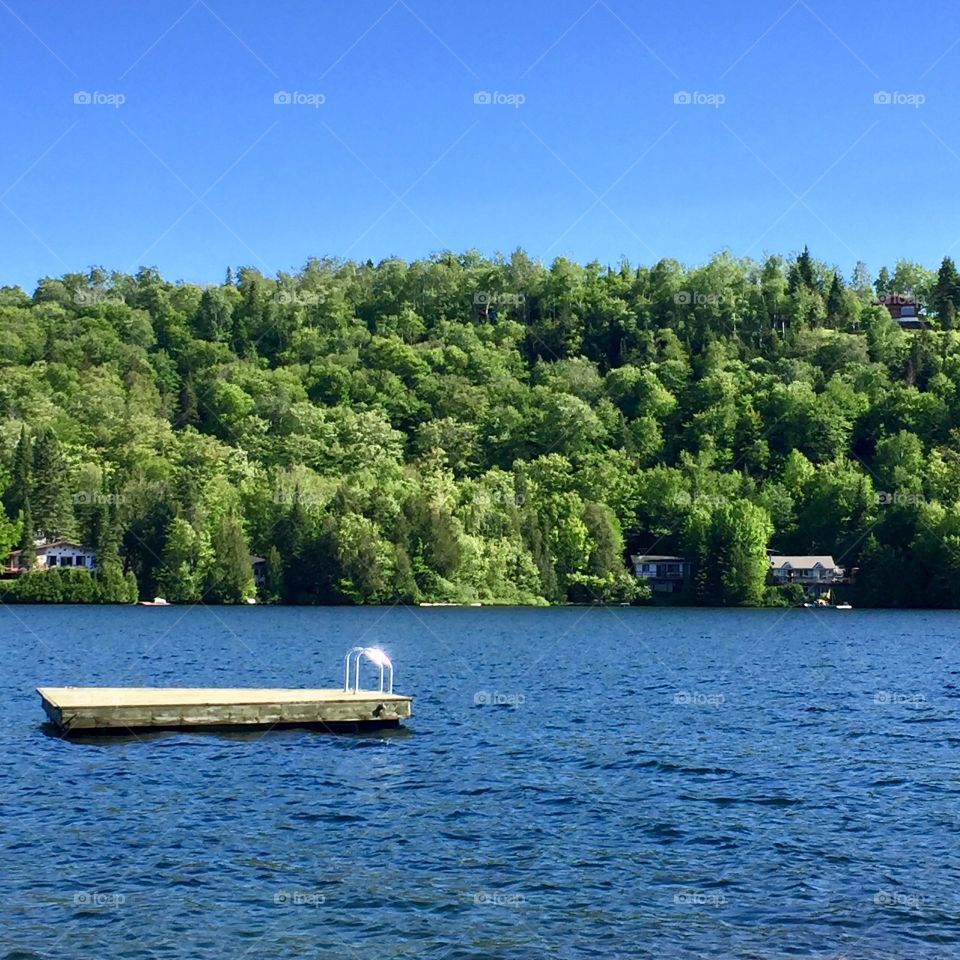 Floating dock on the lake. An invitation to jump in the water and enjoy a Summer sunny day in June