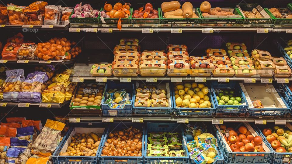 Large counter with vegetables and fruits beautifully stacked in boxes in a store in Brussels Belgium, close-up side view. The concept of healthy eating, offline shopping.