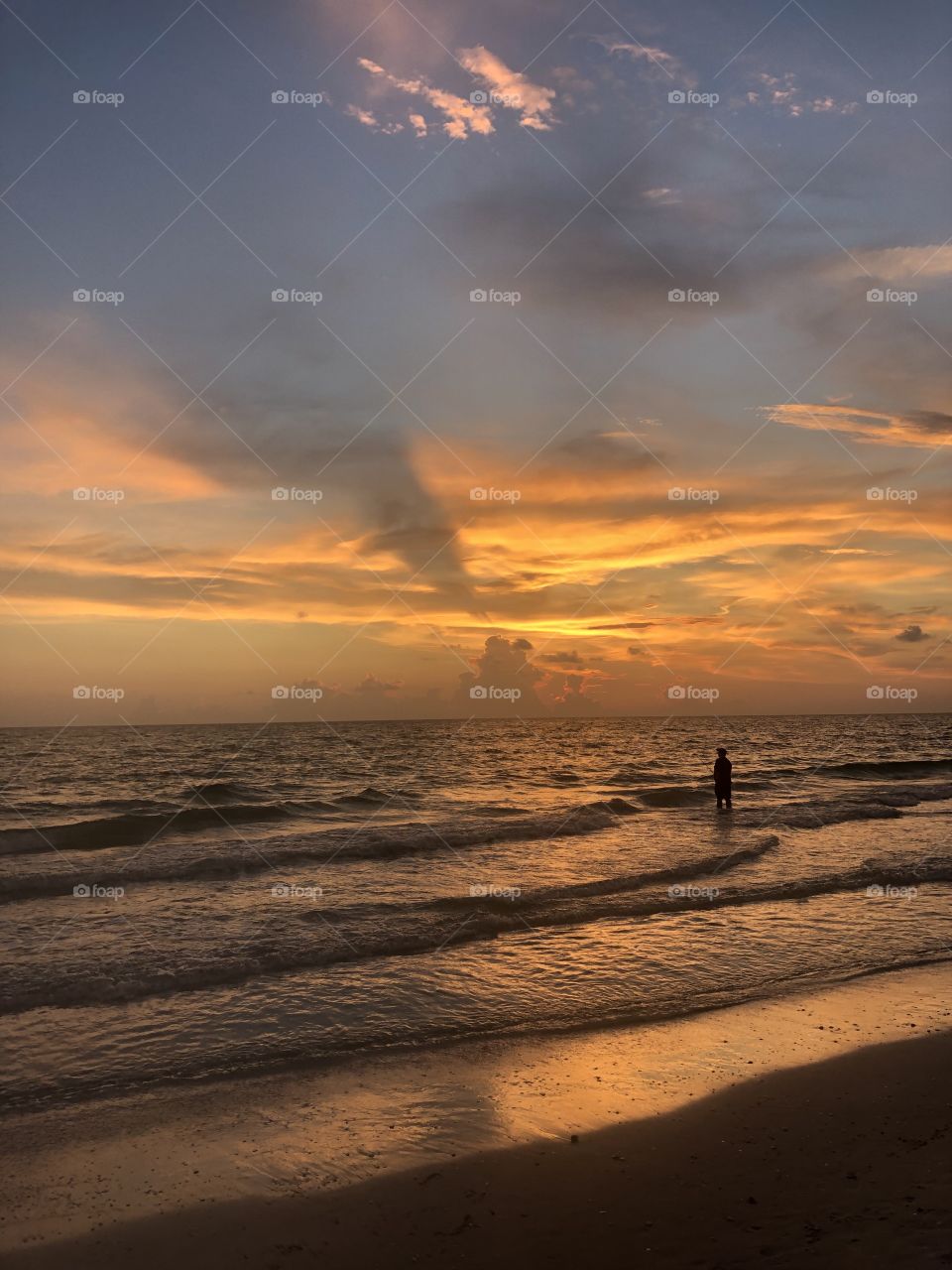 Standing in the waves during peaceful sunset 