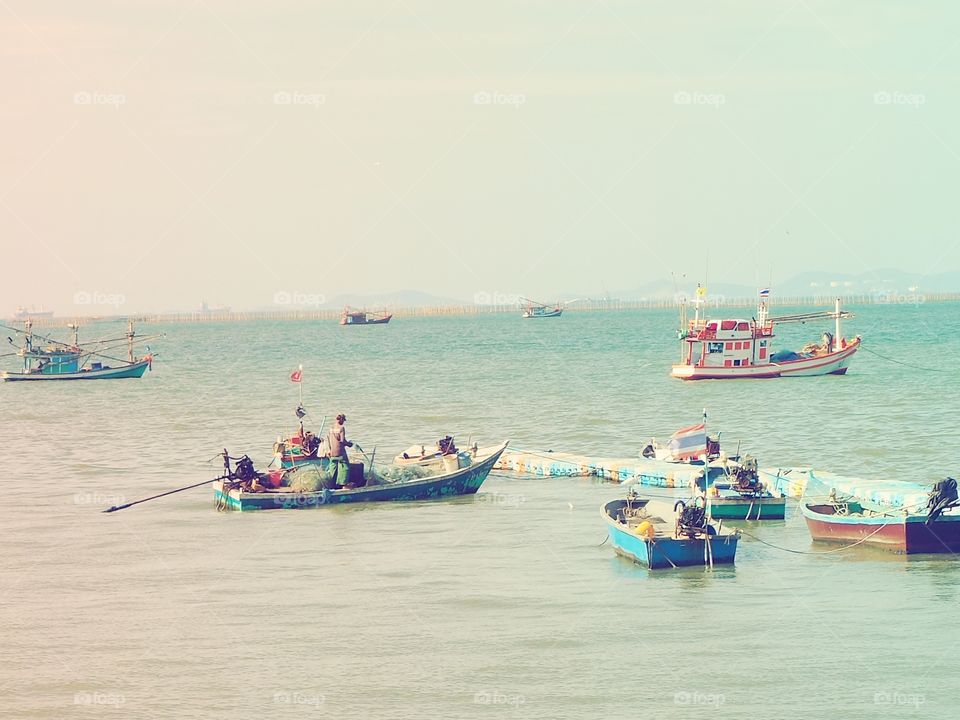 Fisherman pulling his fishing net surrounded with other small boats.