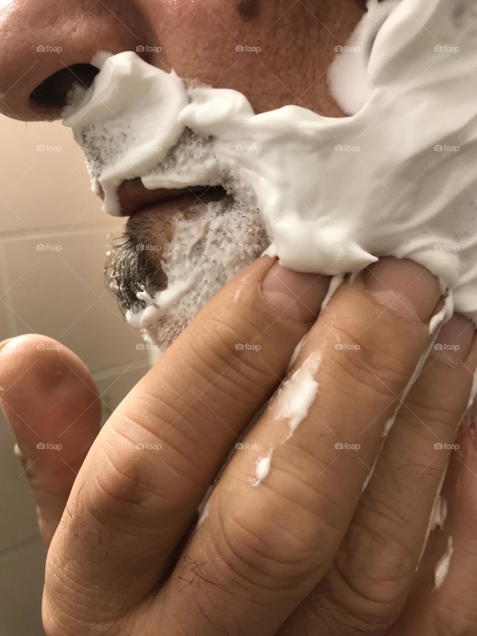 the man applies a generous amount of shaving cream to his face