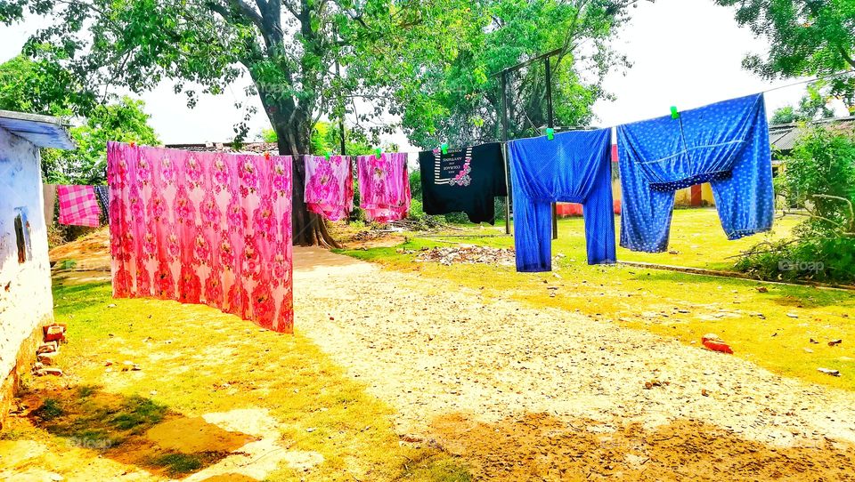 This is the summer season. The clothes are being dried outside. It looks beautiful when clothes are colourful with nature.