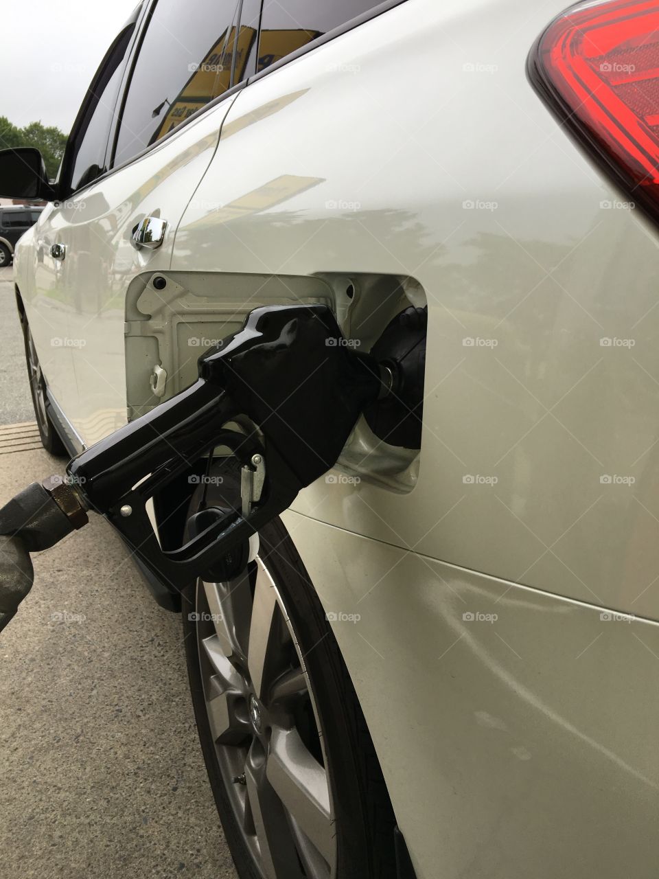 Low view of car getting fillip with black handle set to auto. Shows tire, cement, side of car. 