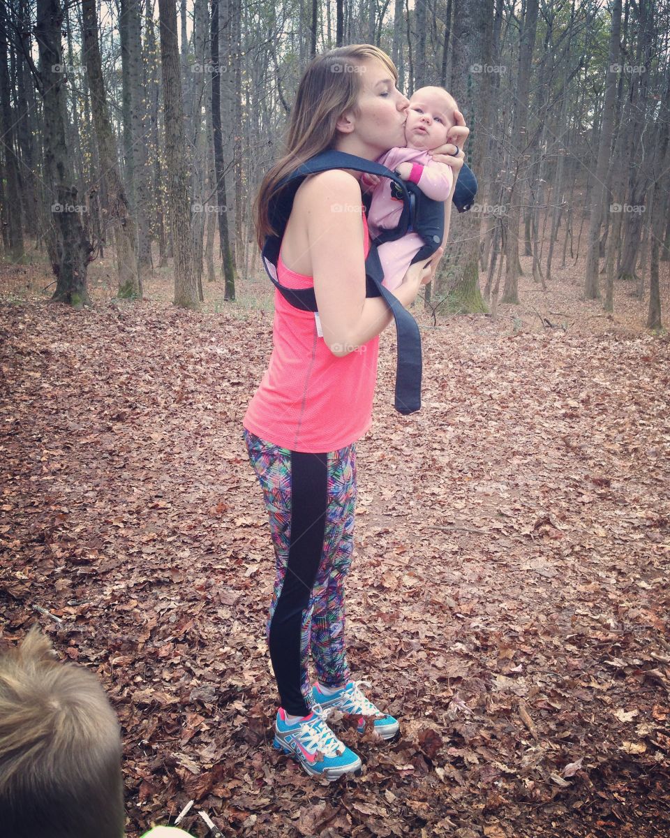 Mother kissing her baby in forest