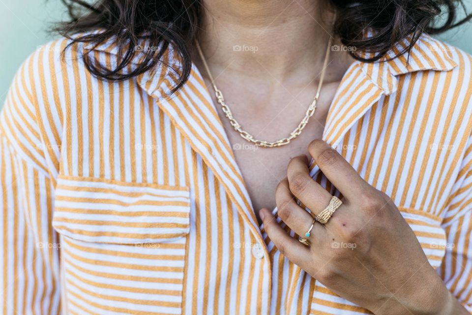 Woman wearing gold jewellery, together with colorful clothing on a summer day.