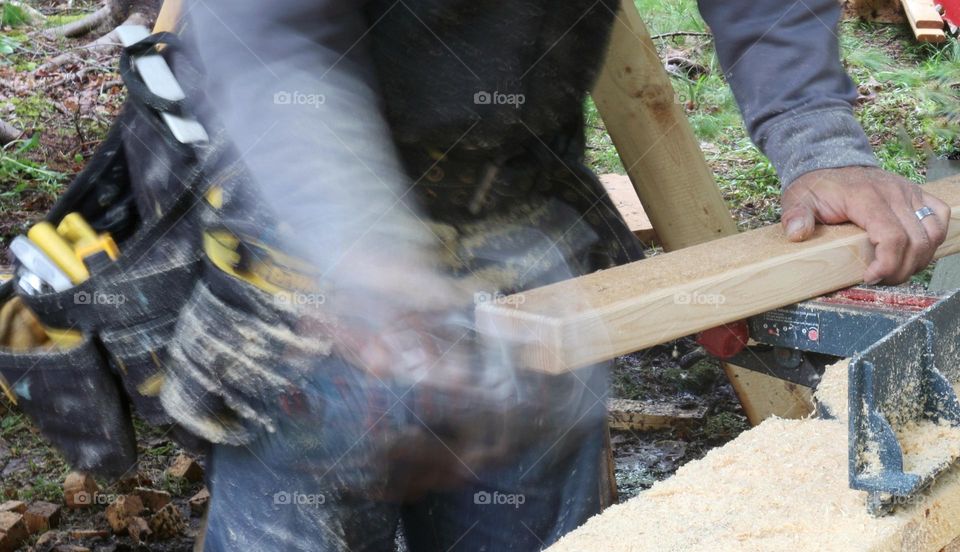 A carpenter routers a piece of wood.