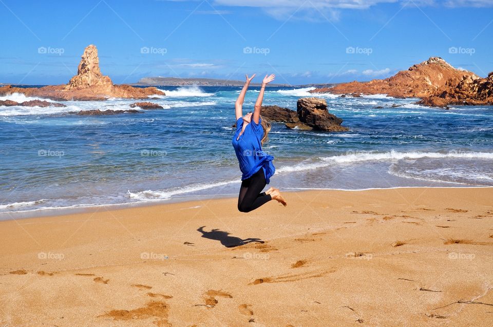 irl jumping on pregonda beach on menorca Balearic island in Spain