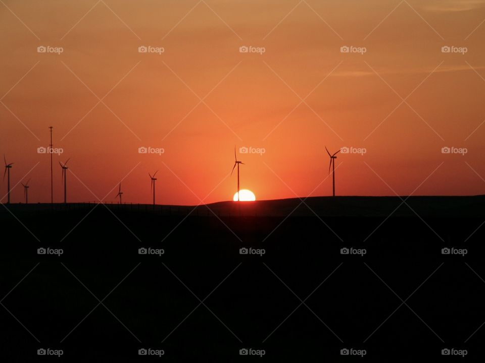 Subtle Sunset. Warm orange sky across the Kansas plains at a wind farm while the sunset retreats slowly  behind the horizon.