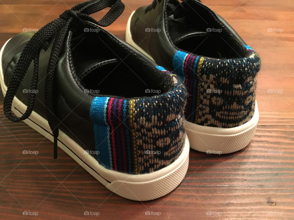 Embroidered textile sneaker shoes from Peru - no two the same. Close up on the embroidered heel art. Black leather with white rubber soles.