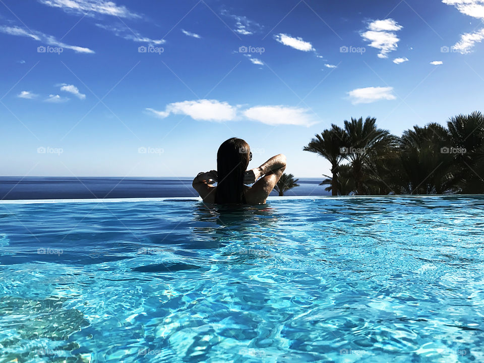 Woman in blue swimming pool during tropical vacation 