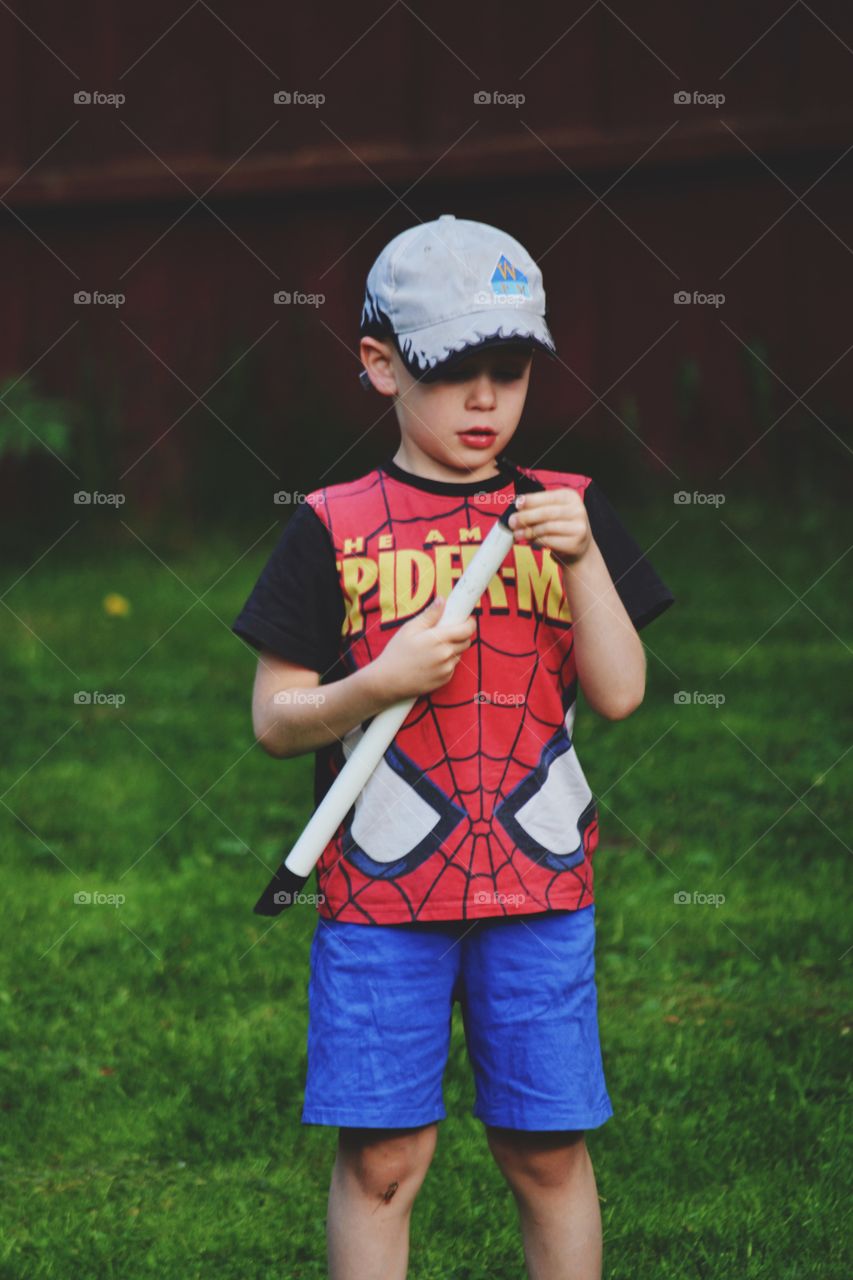 Boy playing in the backyard wearing a cap and spiderman shirt