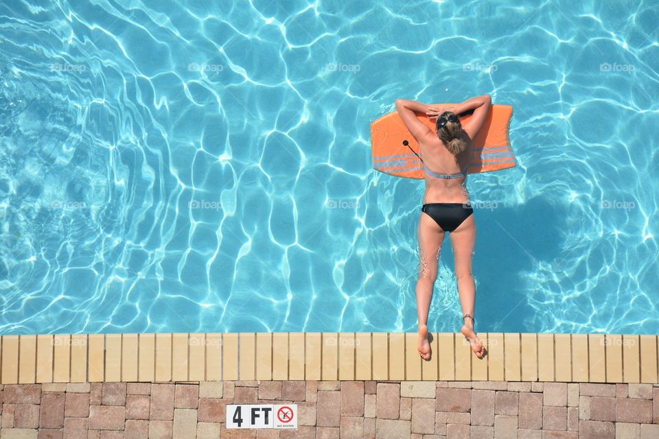 A girl suntanning in the swimming poo.