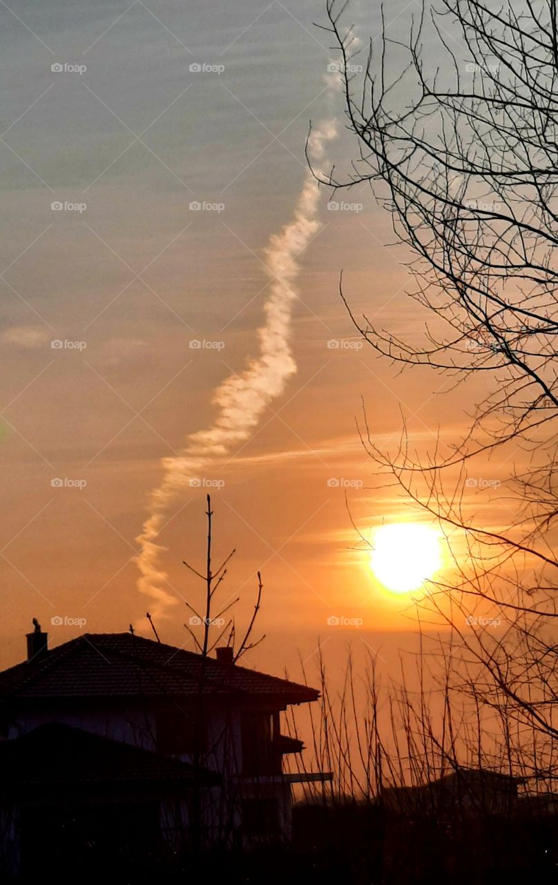 sunrise in March with orange sky and  fancy condensation plume