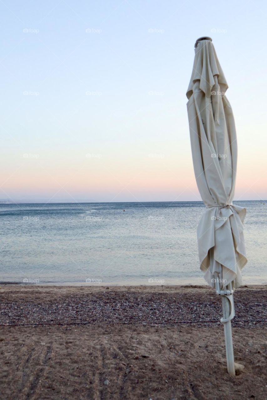 Blue sea at sunset time with close parasol on the beach