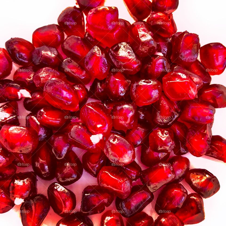 Flatlay image of Pomegranate arils on a white surface 
