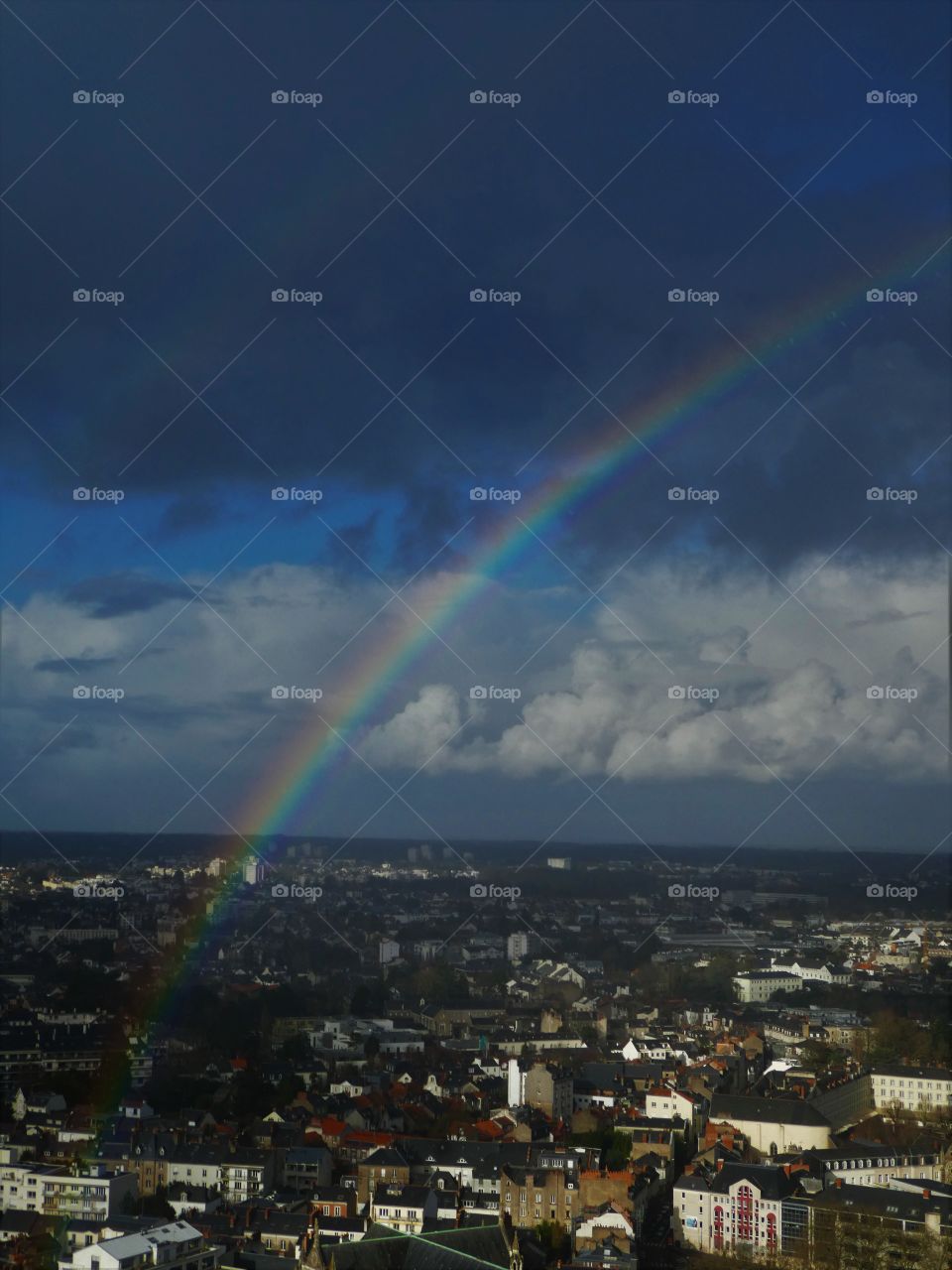 landscape of a city with a rainbow and a storm at the top
