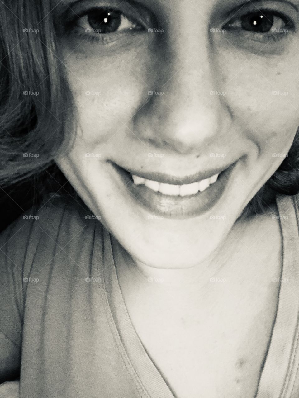 A black-and-white, close-up self portrait of a young lady with a huge smile