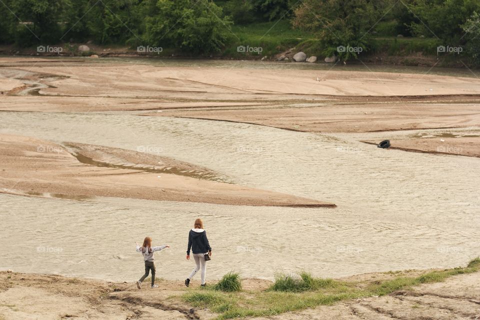 Mom and daughter go to the shallow river