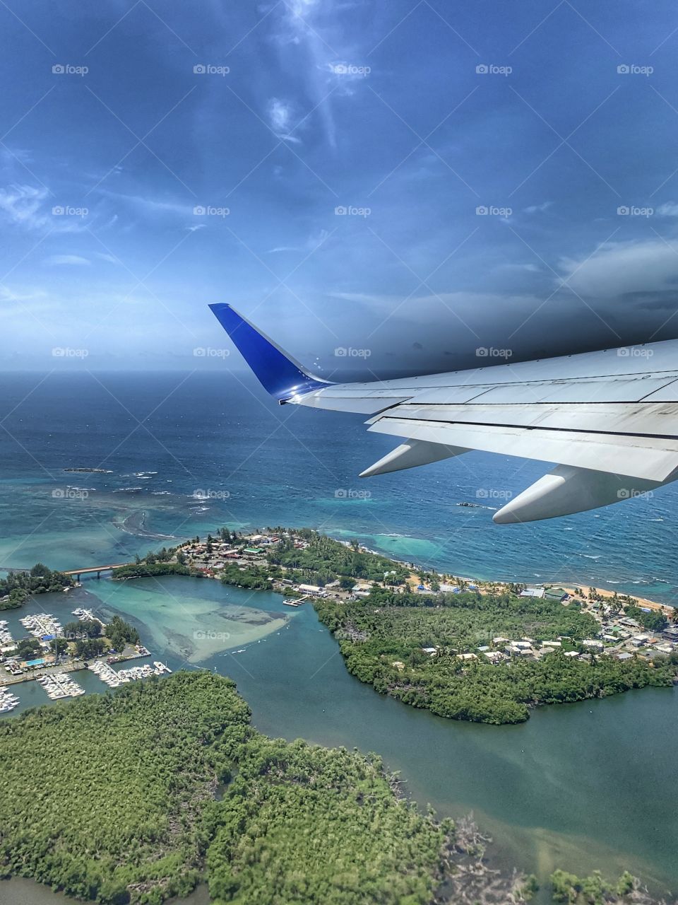 Airplane wing, blue sky, white clouds, weather, sunny day, traveling, flying, space. Isla verde San Juan, Puerto Rico view from above.